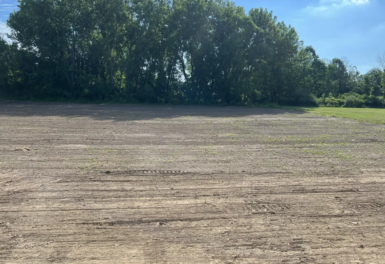 Yard graded smooth and shaped to drain, tracked machine marks still in the dirt